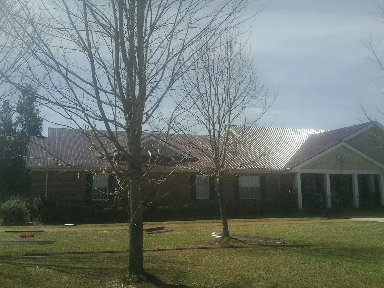 Red metal roof on a brick building seen from the front lawn in Pierce