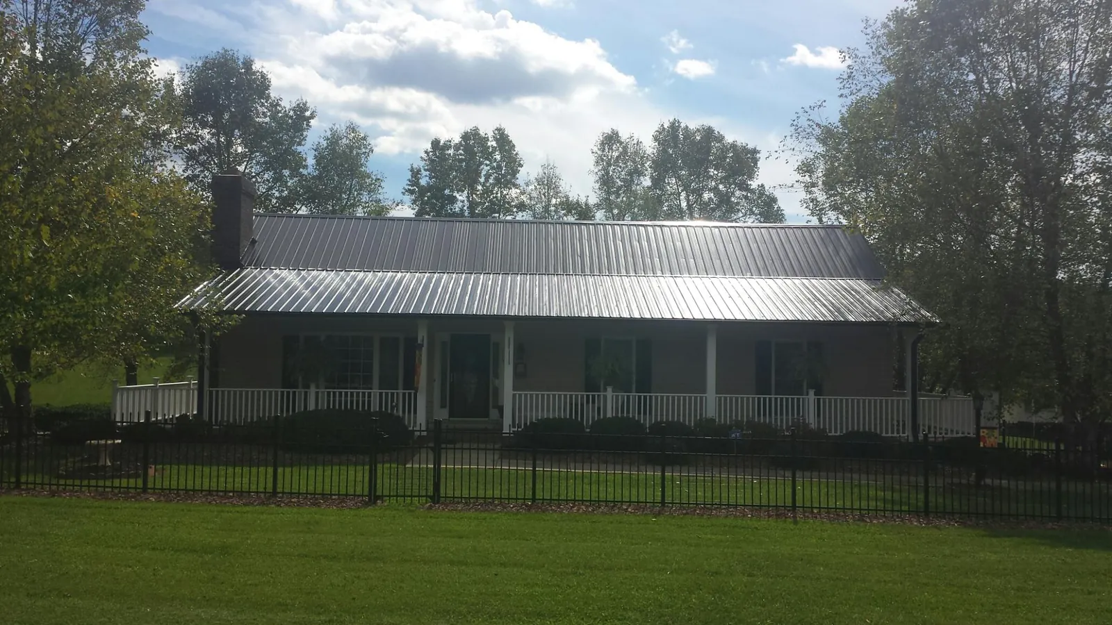 Gray metal roof on a brick ranch with a full width front porch — Gutter Guard Installation work by our crew in Pierce
